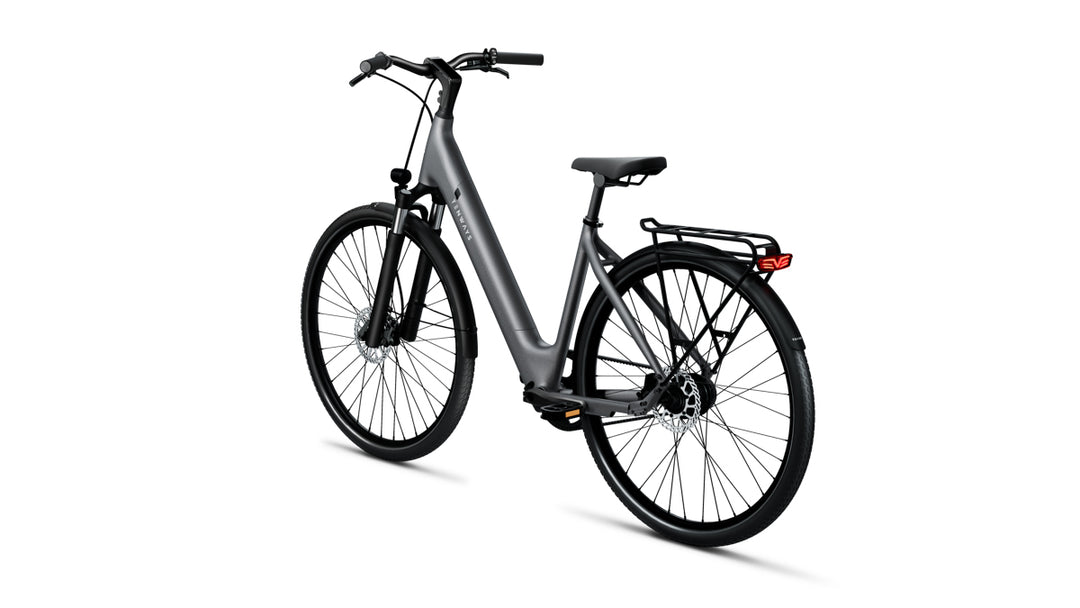 Rear-left profile of Tenways 800S electric bike in Pebble Grey with a step-through frame, integrated battery, belt drive system, front suspension fork, and rear rack.